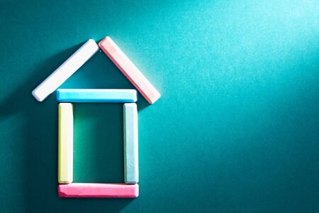 Close-up of colorful pieces of chalk put in form of house on blackboardの写真素材
