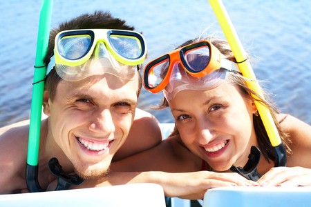 Portrait of cheerful couple in aqualungs looking at camera with smilesの写真素材