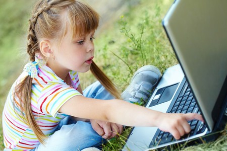 Portrait of curious girl looking at the laptop while touching a keyの写真素材