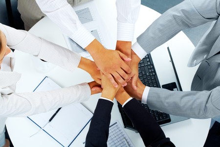 Above angle of business partners making pile of hands over workplace  