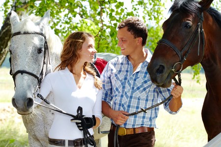 Image of happy couple with purebred horses looking at each otherの写真素材