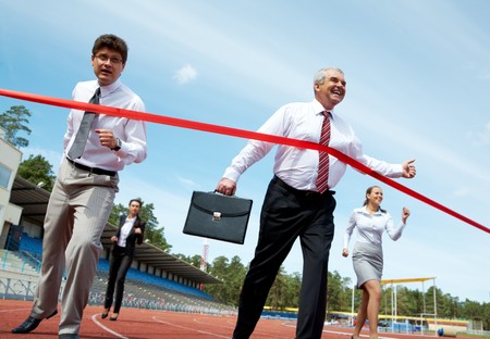 Photo of happy mature businessman crossing finish line during race の写真素材