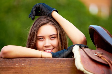 Image of happy female holding saddle and looking at cameraの写真素材