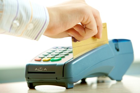 Close-up of human hand putting credit card into payment machine in shopping centerの写真素材