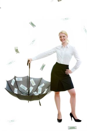 Happy businesswoman catching dollar bills into open umbrellaの写真素材