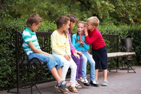 Portrait of happy friends resting on bench in park and chattingの写真素材