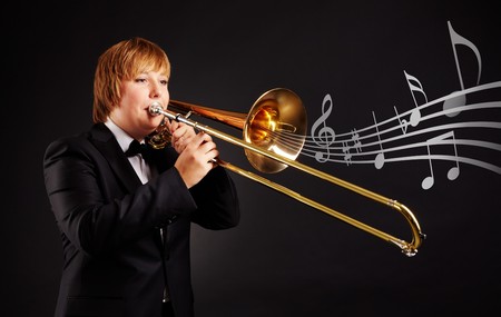 Portrait of young female playing the trombone on black backgroundの写真素材