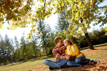 Photo of happy girl with handsome male relaxing outdoors in autumnの写真素材