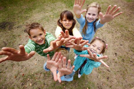 Portrait of happy friends standing on ground in park and stratching armsの写真素材