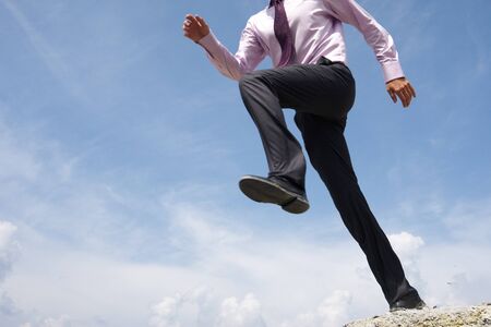 Close-up of running man on background of bright blue sky with white cloudsの写真素材