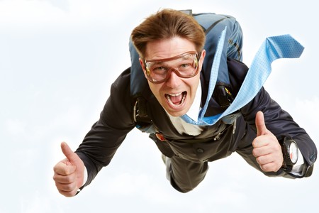 Conceptual image of happy man flying with parachute and showing thumbs upの写真素材