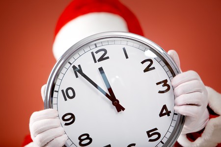clock in Santa hands showing five minutes to midnightの写真素材