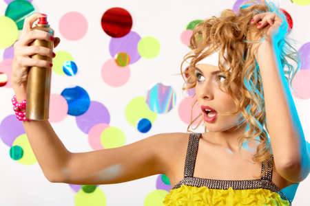 glamorous lady spraying hair lacquer before herselfの写真素材