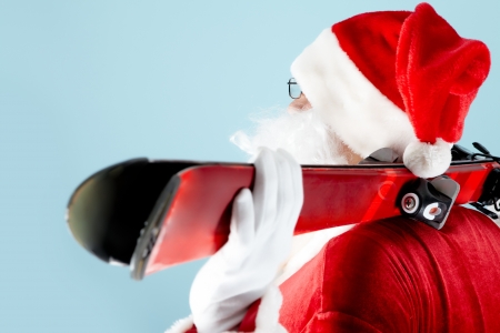 Side view of Santa Claus with skis on blue backgroundの写真素材