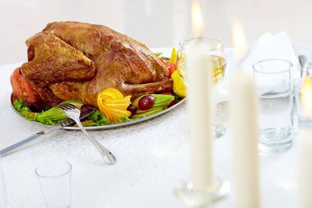 Image of roasted turkey with flutes of wine and burning candles on Christmas tableの写真素材