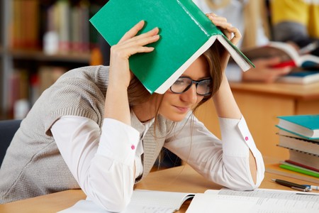 Portrait of clever student reading book in college libraryの写真素材
