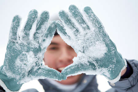 Photo of guy showing gloved hands covered with snow の写真素材