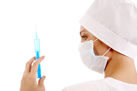 Nurse in mask looking at syringe needle while checking volume of medicine in itの写真素材