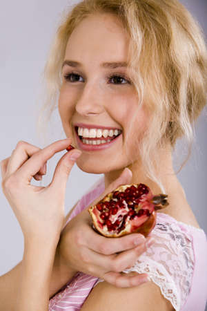 Portrait of a beautiful blonde woman with the pomegranate in her handの写真素材