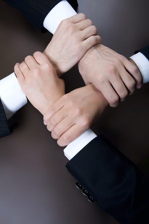 Isolated on black four crossed human hands in business wear