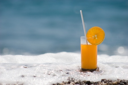 Close-up of orange juice with foaming wave surging on the shoreの写真素材