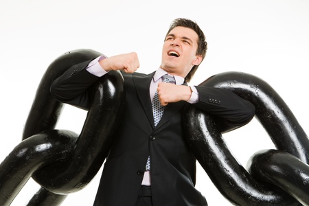 Portrait of tense businessman with two sections of heavy chain over white backgroundの写真素材