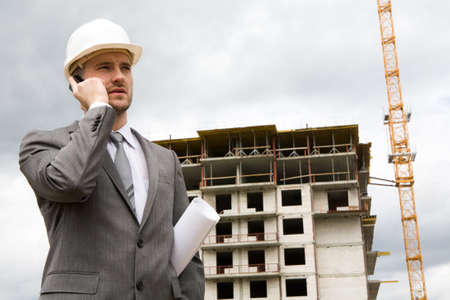 Portrait of confident foreman calling by mobile phone at building site 