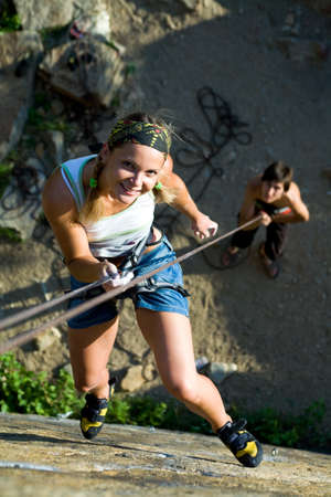 Image of woman hanging on the rope and man standing by herの写真素材