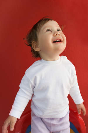 Portrait of happy toddler looking upwards over red backgroundの写真素材