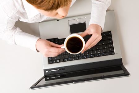 Photo of woman holding cup of coffee at workplace の写真素材