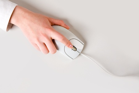 Womans hand touching computer mouse placed on white table の写真素材
