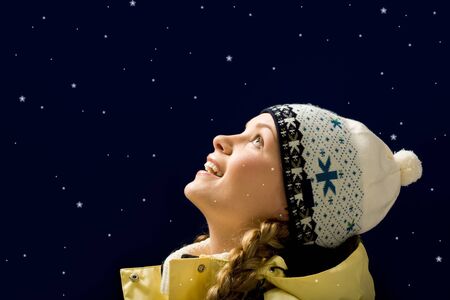 Portrait of amazed girl looking at falling snowflakesの写真素材