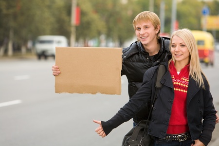 Photo of pretty girl and handsome guy hitchhiking on city road