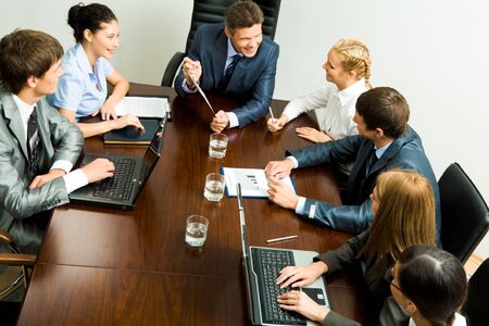 Above view of young co-workers working with papers and consulting each other