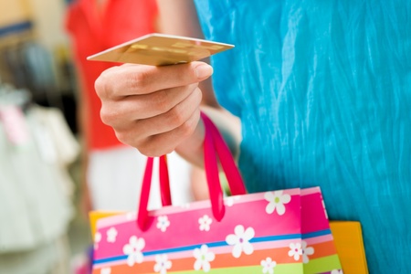 Image of female holding card in hand ready to pay for her shoppingの写真素材