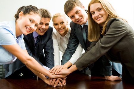 Portrait of happy business team keeping their hands on top of each other 