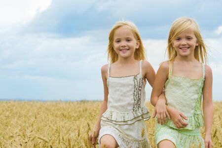Portrait of cute twins walking down wheat field and smilingの写真素材