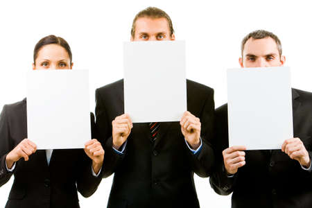 Row of three business partners holding blank papers by facesの写真素材