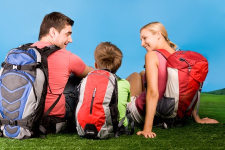 Rear view of family chatting on grassland during rest over blue background の写真素材