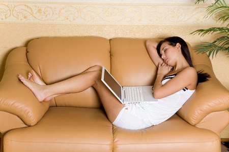Image of pretty girl sleeping with laptop on leather sofaの写真素材