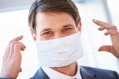 Portrait of businessman holding protective mask before himselfの写真素材
