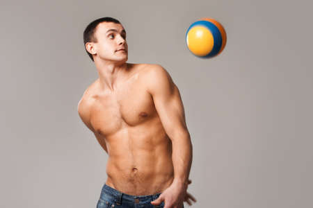 Photo of shirtless man looking at ball thrown behind his backの写真素材