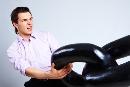 Portrait of frantic businessman pulling section of heavy chain and screamingの写真素材