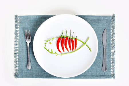 Image of plate with hot chili peppers and asparagus in form of fish
