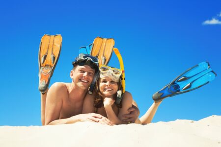 Happy family with flippers lying on sand and looking at camera の写真素材