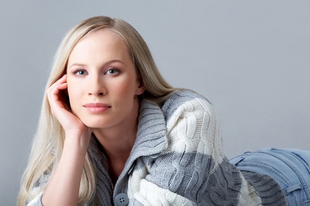 Portrait of blond female in woolen cardigan looking at cameraの写真素材