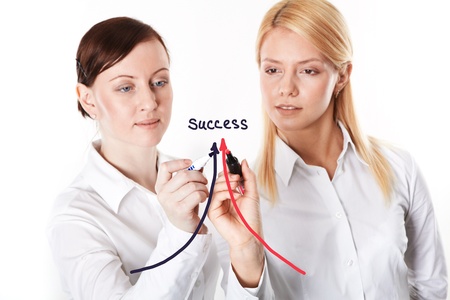 Two businesswomen drawing arrows leading to successの写真素材