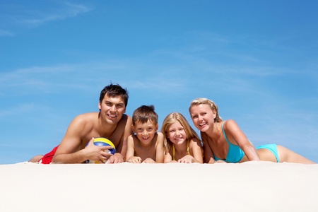 happy family lying on sand on summer vacationの写真素材