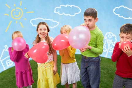 Group of happy children inflating balloonsの写真素材