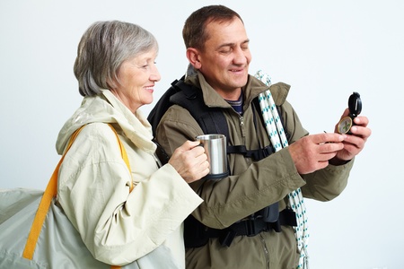 Portrait of happy senior couple looking at compass on trip
